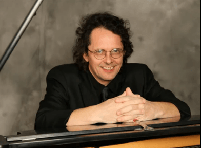 Andrew sitting in front of a piano