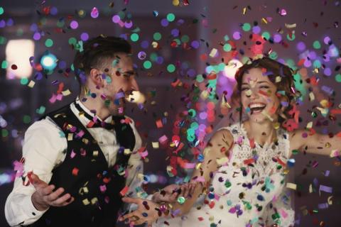 A bride and groom surrounded by confetti 