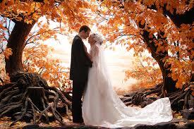 A bride and groom near autumn trees 