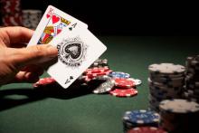 Someone holding cards at a casino table 