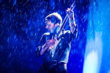 A man playing guitar in the rain 